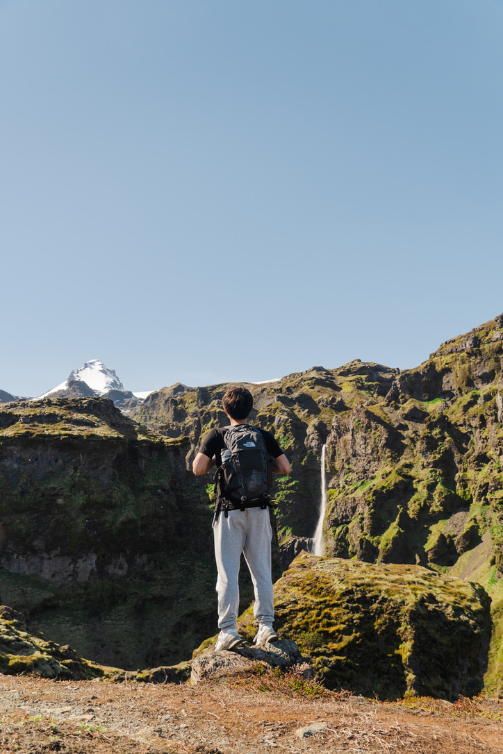 Allen overlooking a mountain landscape with waterfall